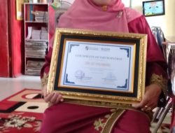 Senyum Kepuasan Terpancar Hj Jarimis S.Pd Saat Menerima Penghargaan IOM